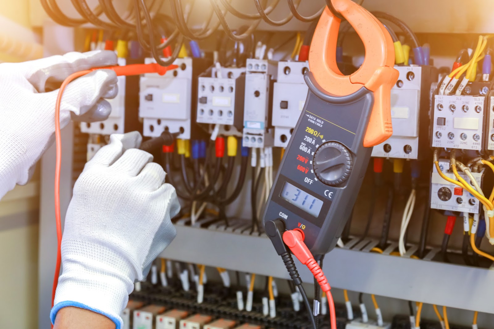 electrician measurements with multimeter tester in control panel.